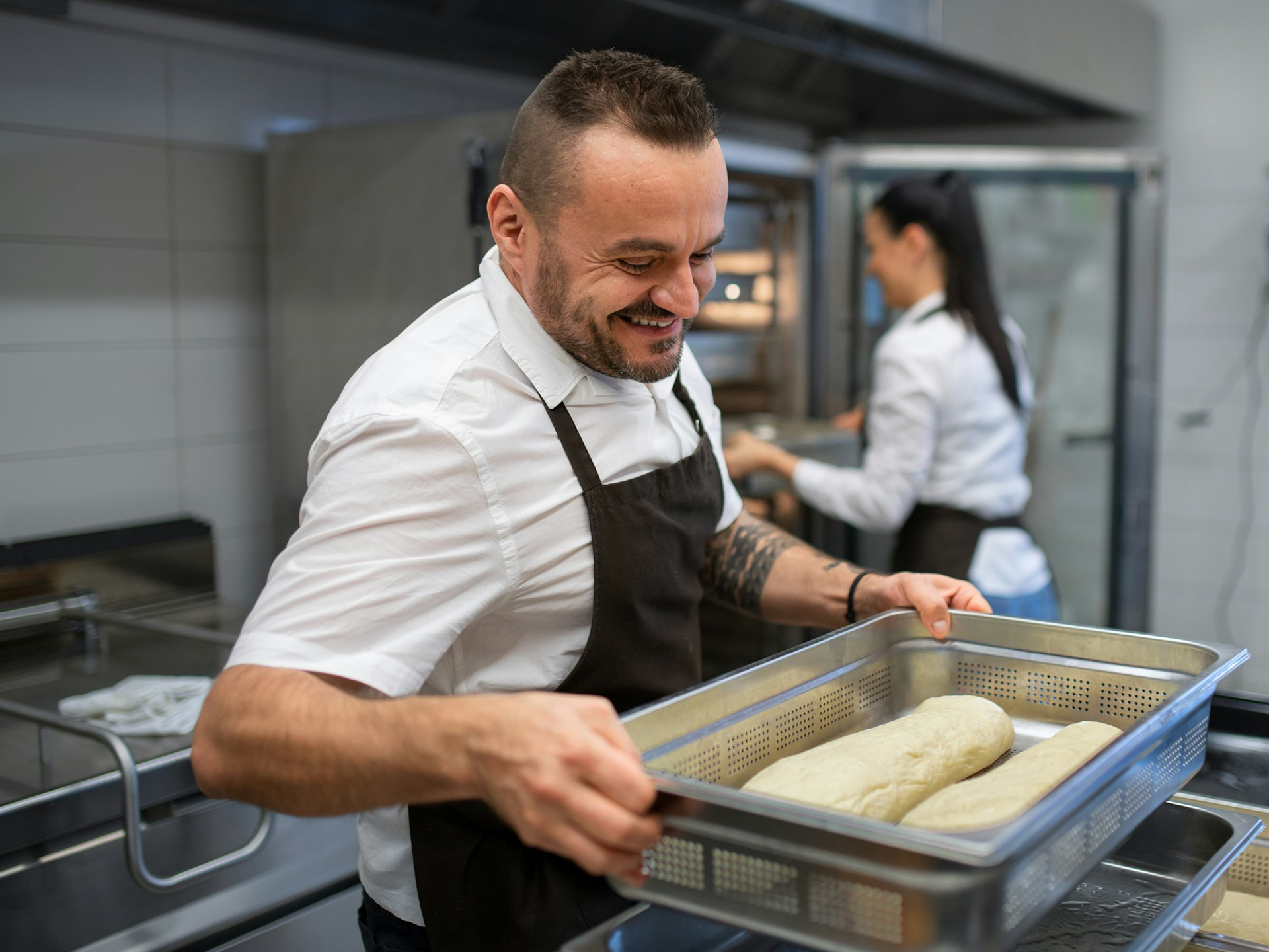 mand med forklæde holde plade med dej og pige åbner en ovn